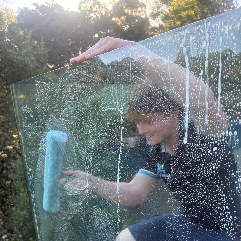 AW technician scrubbing glass with a soft applicator and cleaning solution