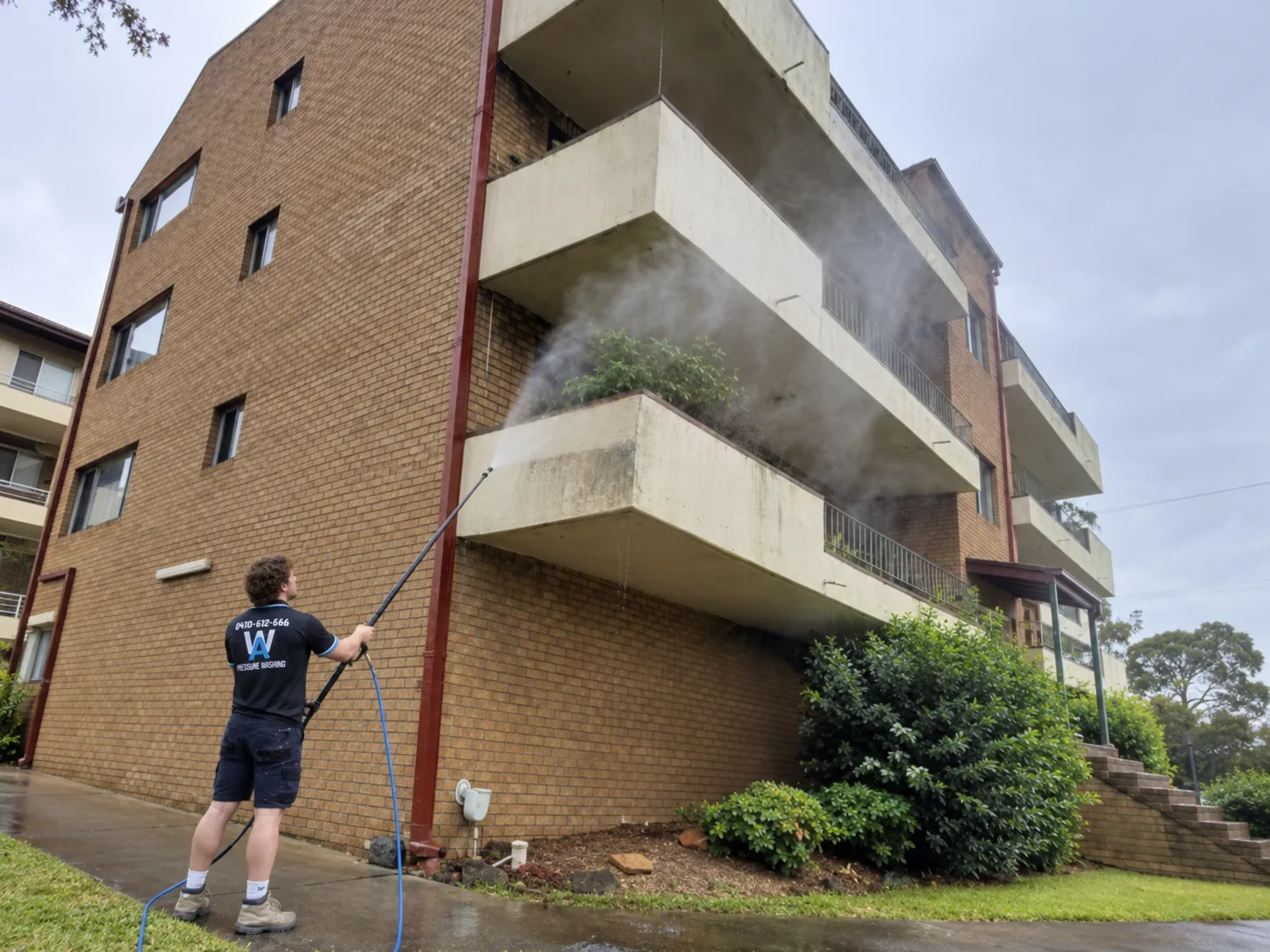 AW technician washing the exterior of a strata apartment building