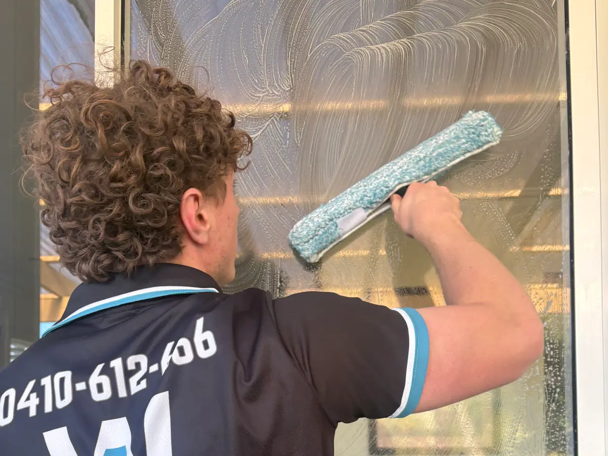 AW technician scrubbing a window in branded uniform